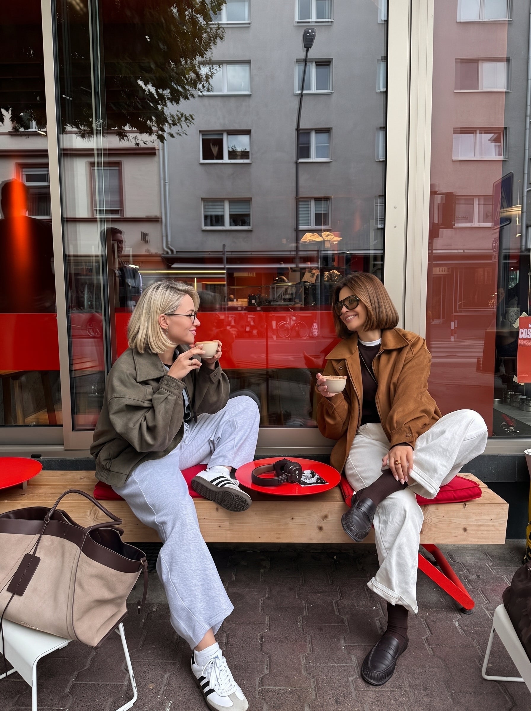 Zwei Frauen sitzen vor einem Café und genießen Kaffee