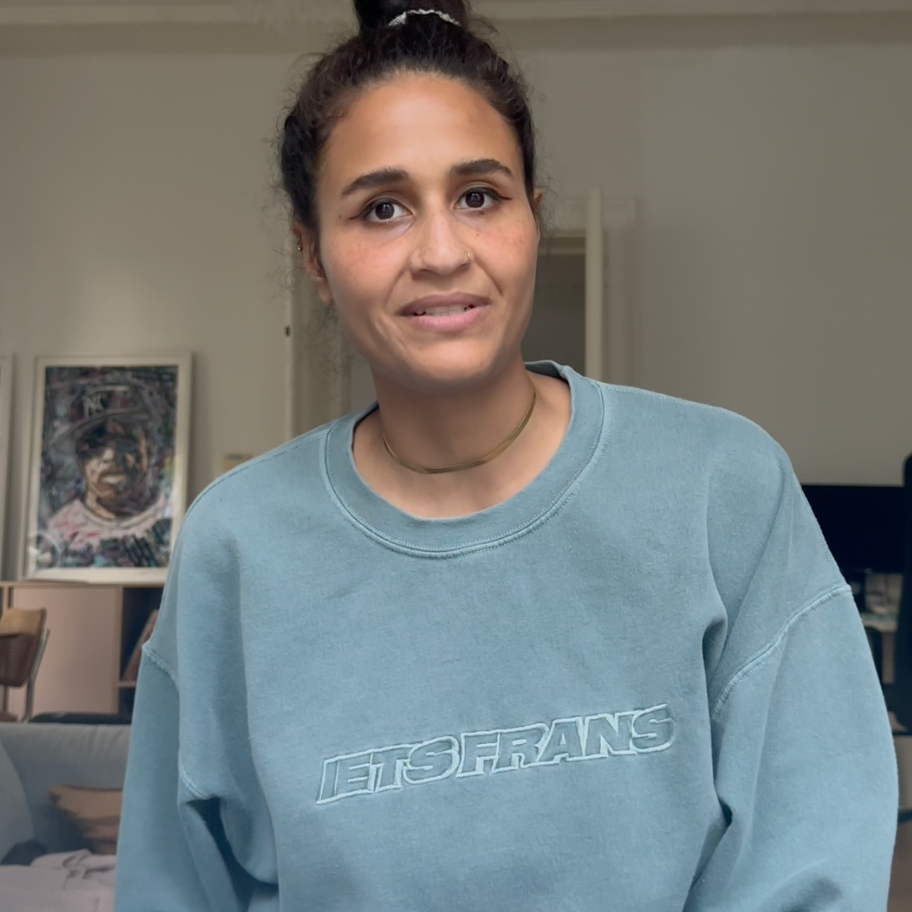 Junge Frau mit Dutt in hellblauem Sweatshirt spricht in einer Videobotschaft