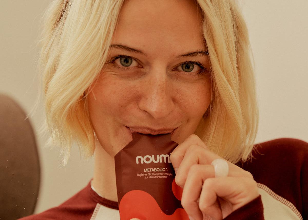 Blonde Frau trinkt direkt aus einem noumi Metabolic-1 Sachet