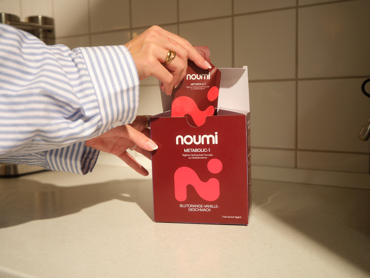 Hände nehmen ein noumi Metabolic-1 Gel-Sachet aus der Box in der Küche