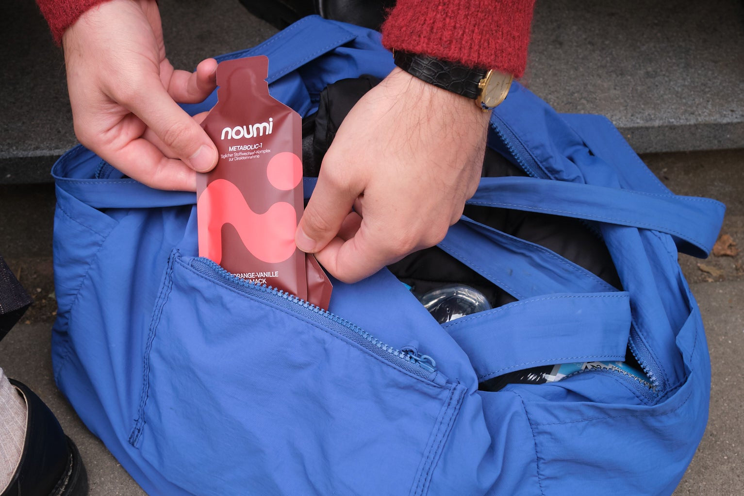Hände packen ein noumi Metabolic-1 Gel-Sachet in eine blaue Tasche