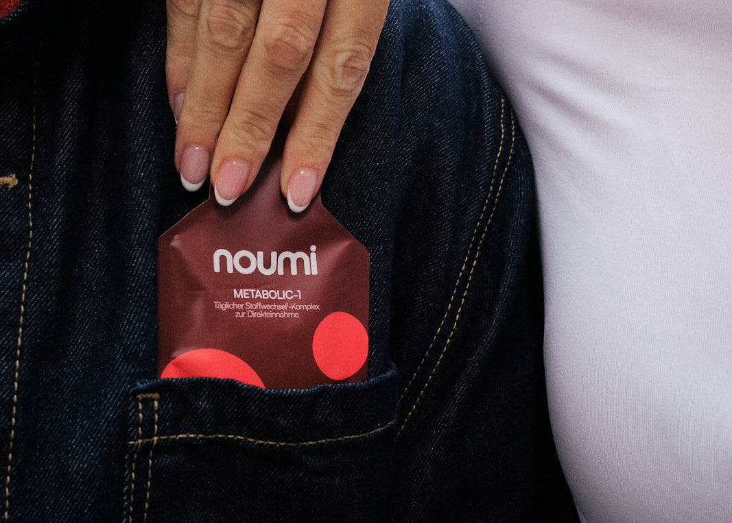 Hand zieht ein noumi Metabolic-1 Sachet aus der Jeanstasche